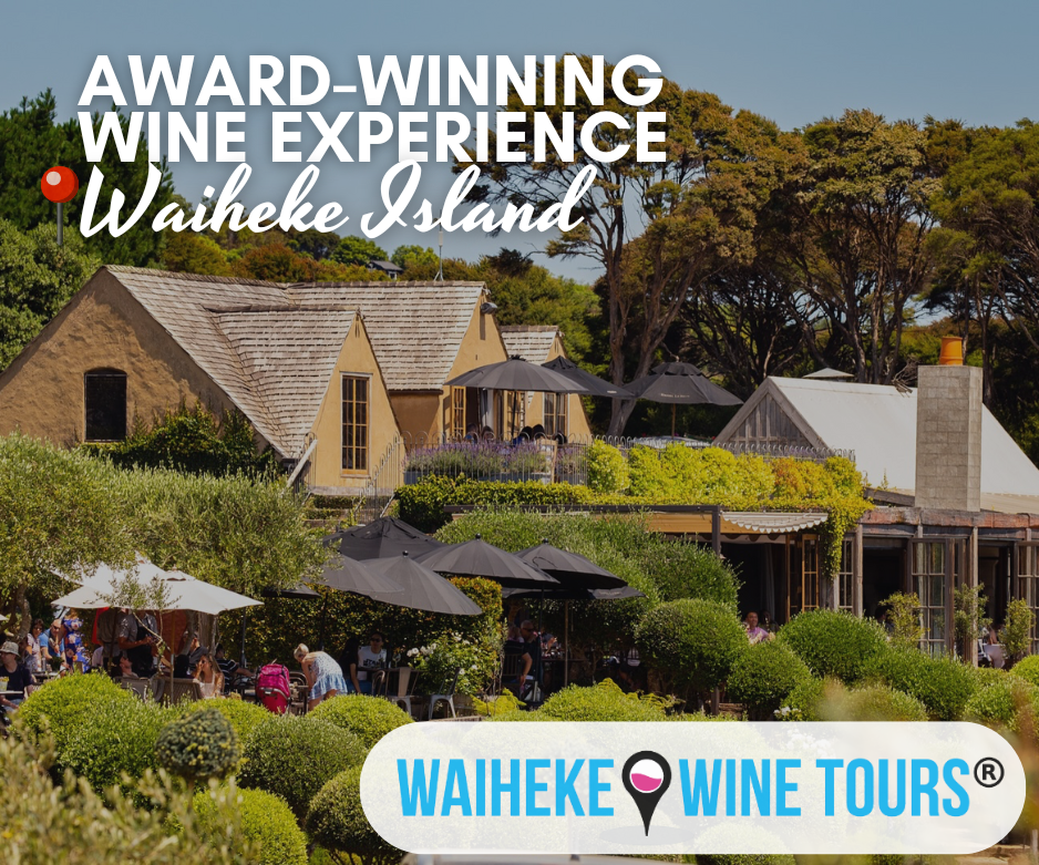 Visitors enjoy a sunny afternoon at a vineyard restaurant surrounded by lush greenery, with rustic buildings and outdoor seating. Text reads “Award-Winning Wine Experience – Waiheke Island”