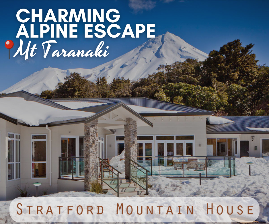 Stratford Mountain House in a snow-covered alpine setting beneath Mt Taranaki, with a modern lodge exterior, stone pillars, and scenic forest backdrop