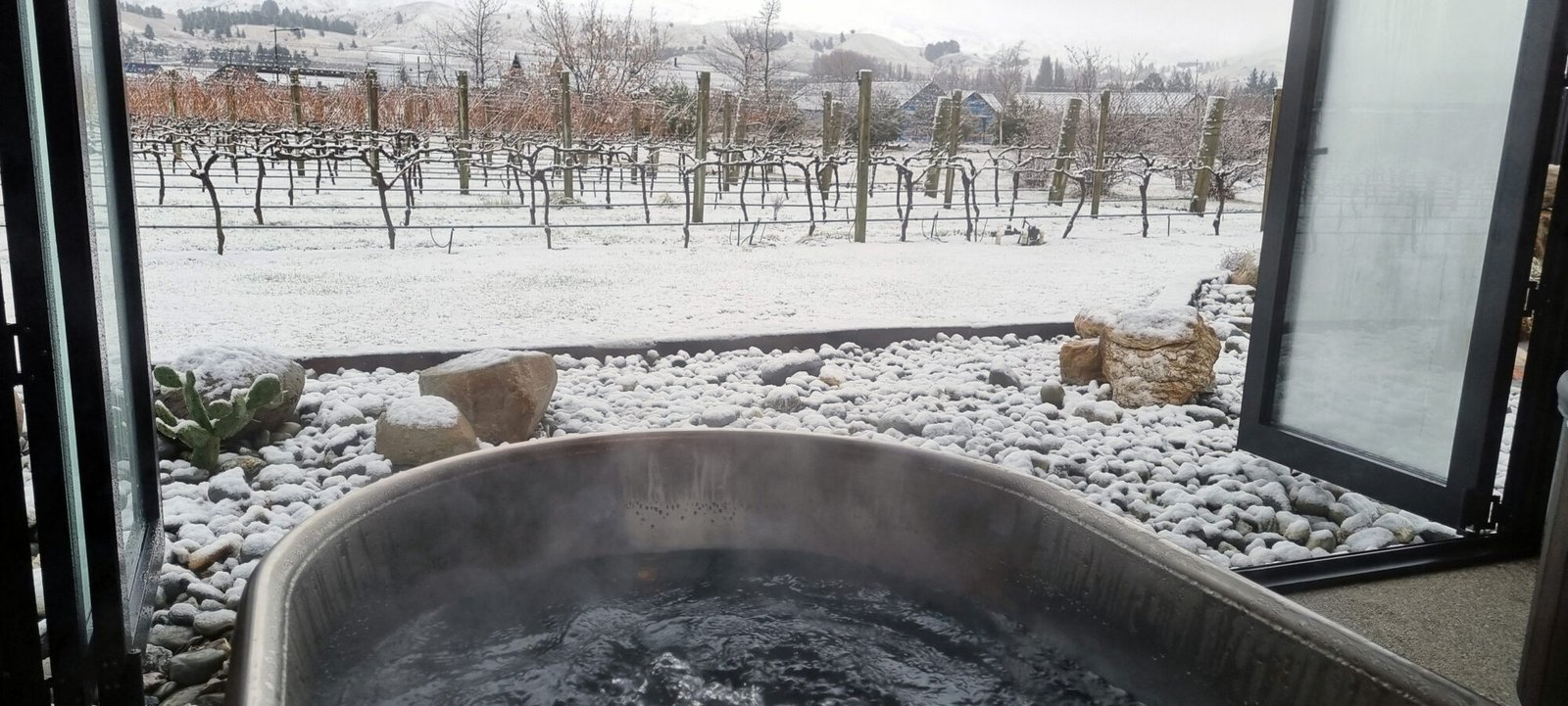 A snowy vineyard scene from hot pool at River Rock Estate in Cromwell, Central Otago