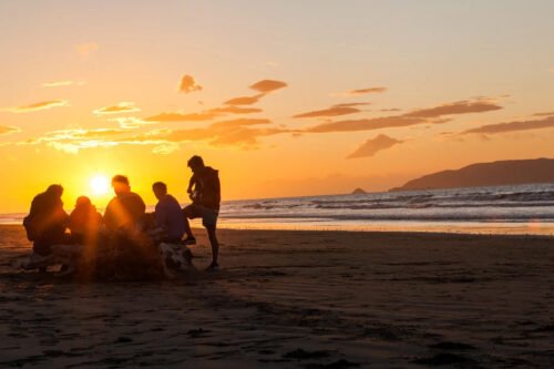 group travel New Zealand friends enjoying beach sunset together