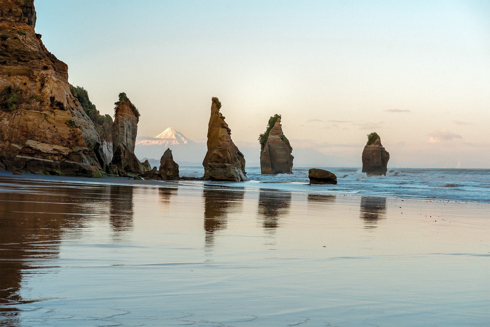 Three Sisters sea stacks reflected on the beach, Tongaporutu Taranaki coastline New Zealand
